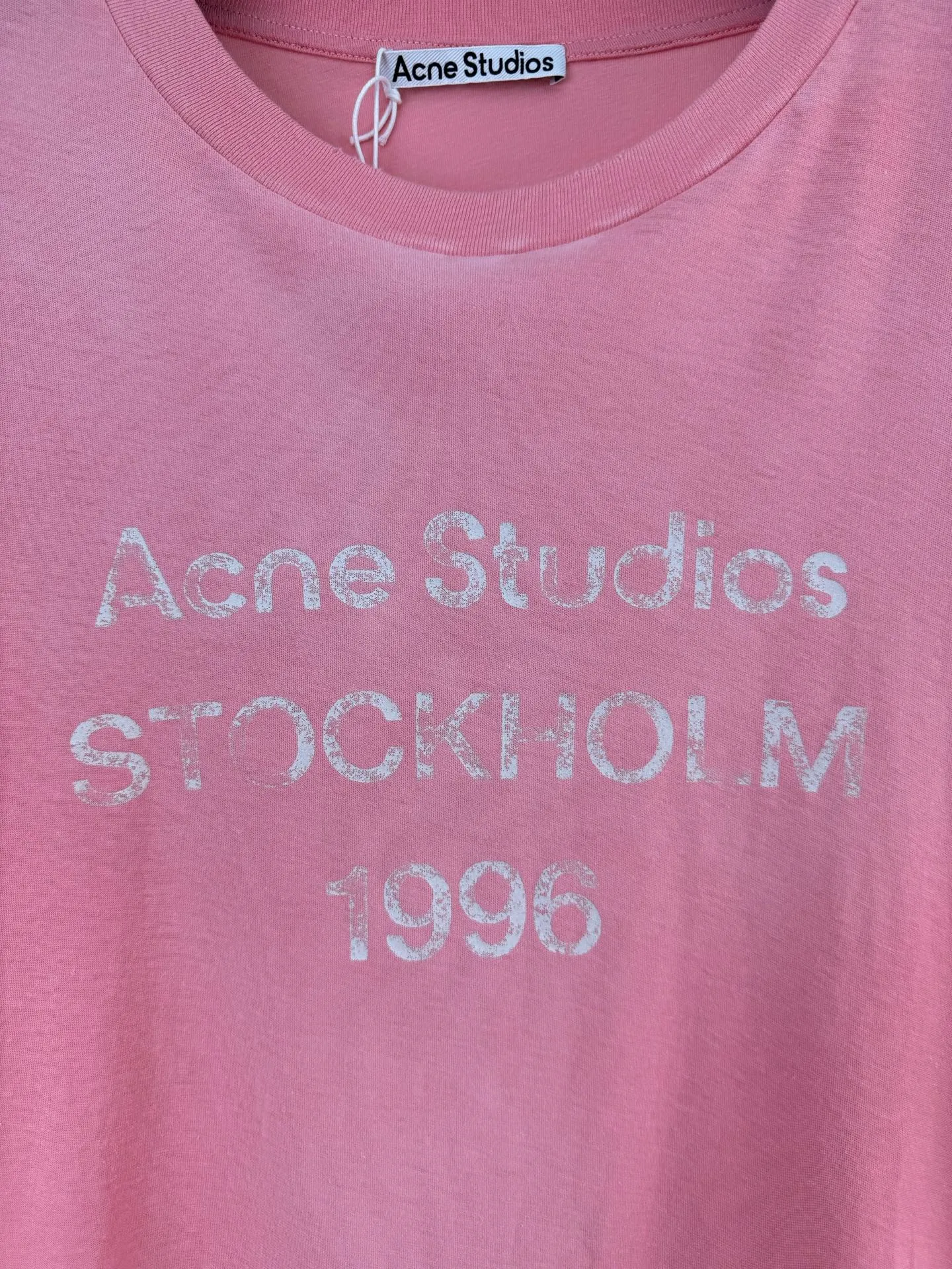 Acne Studio distressed pink fuzzy letter print short-sleeved T-shirt Size: S/M/L/XL Made of 145g/㎡ 85 cotton 15 linen blended jersey jersey. The fabric has been treated with enzyme stone washing and pre-shrinking shaping processes. It combines the softness of cotton and the natural Breathable texture of linen. The fabric surface presents a natural and subtle bamboo texture. The style is a slightly loose straight short long-sleeved cut. The neckline is made of a ribbed crew neck made of this material. The edges of the collar are frayed by hand with distressed raw edges. The inner collar is made of ring-stitched collar technology to resist stretching and sagging for a long time. The front of the body is printed with Retro crack glue printing technology and the ink is treated with aging cracks to restore the worn texture of the vintage. The shoulder seams and side seams are reinforced with four-thread overlock seams, and the cuffs and hem are closed with narrow hems and double-needle flat turning seams. The cotton and linen blended base has a matte washed matte color, with a distressed collar and Retro cracked printing. It combines natural linen and cotton blended fabrics, enzyme washing technology and a relaxed short long-sleeved silhouette, taking into account the suitability for both single wear and inner wear, and fully presents the fine washing and printing process details of Nordic Retro ready-to-wear.